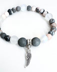 Bracelet with gray and white beads and a silver wing charm on a white background