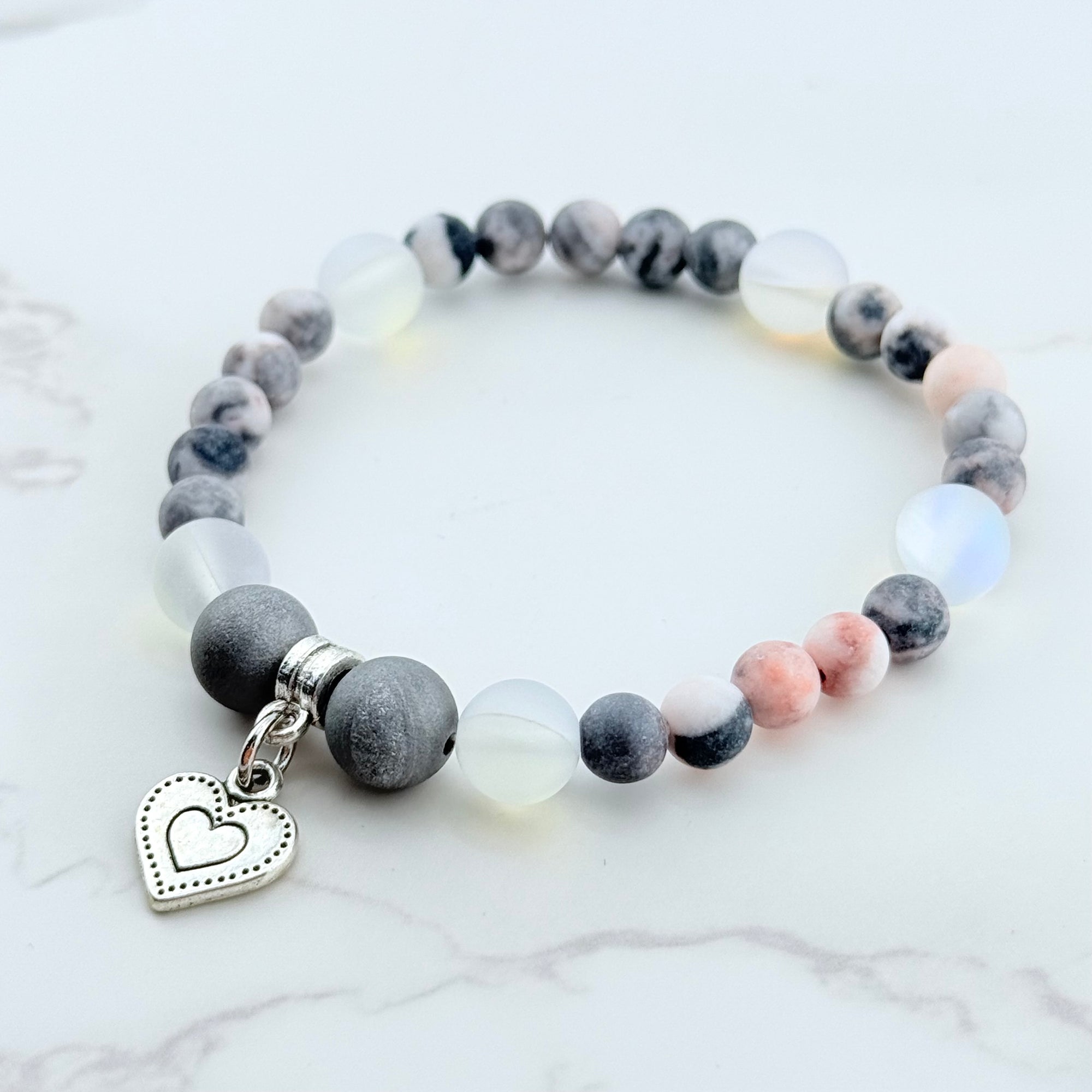 Beaded bracelet with a heart charm on a marble surface