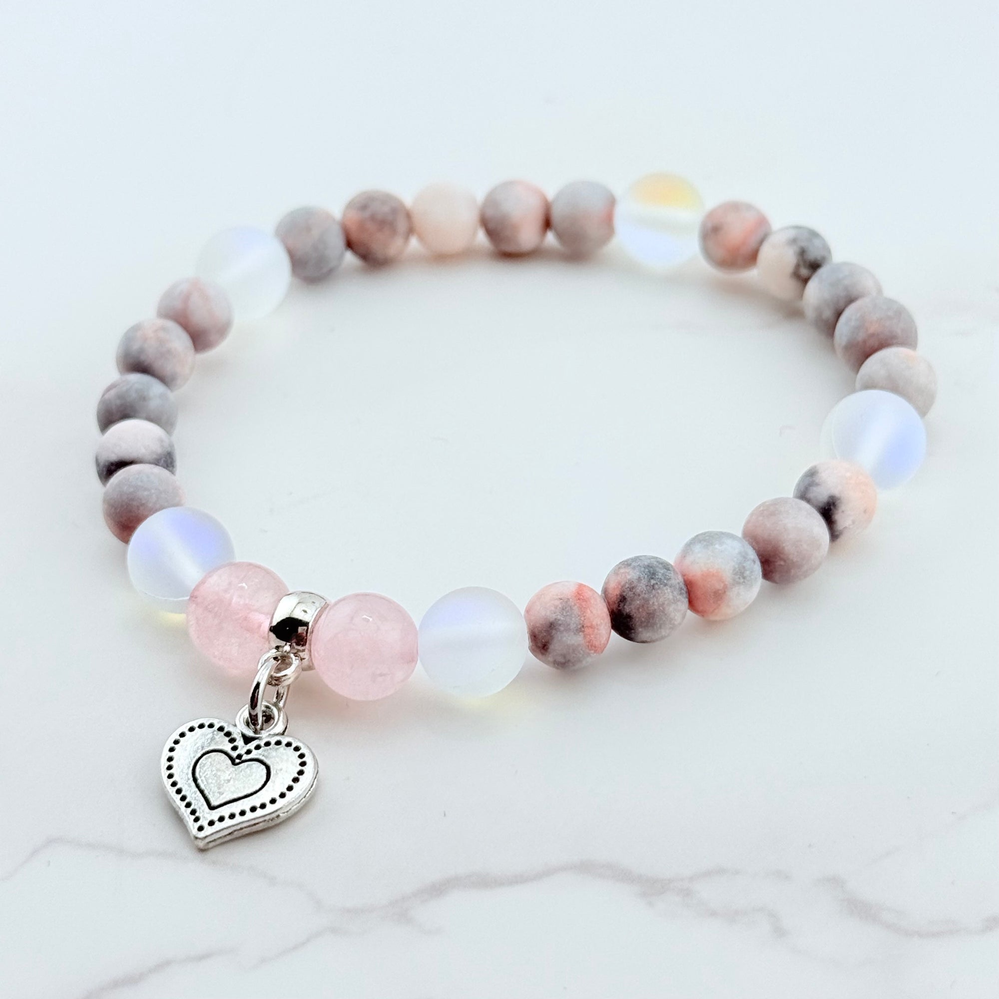 Beaded bracelet with a heart charm on a white background