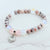 Beaded bracelet with a heart charm on a white background