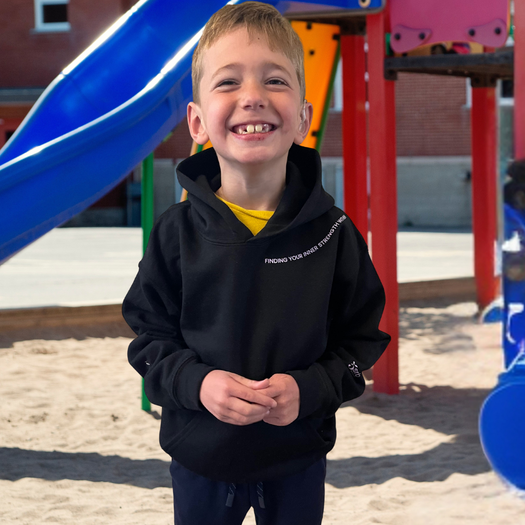 Child wearing a black hoodie with text on a playground