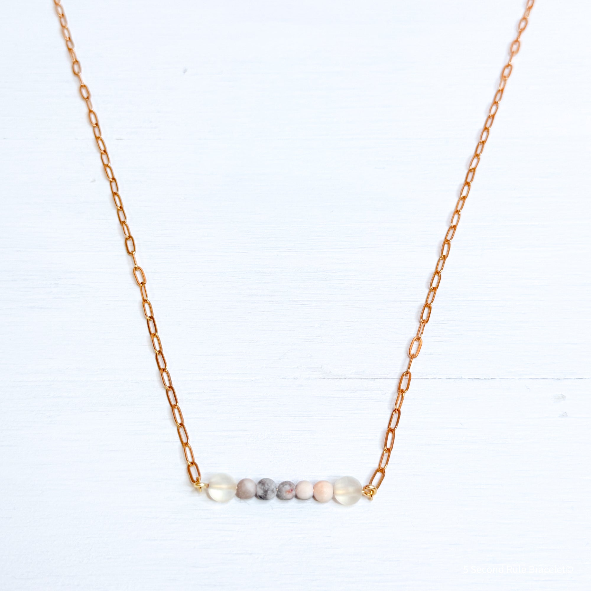 Necklace with small beads on a gold chain against a white background