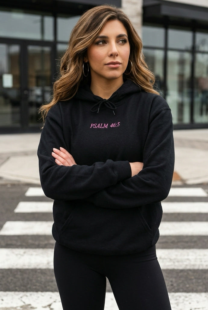 Woman wearing a black hoodie with text, standing on a crosswalk.