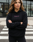 Woman wearing a black hoodie with text, standing on a crosswalk.