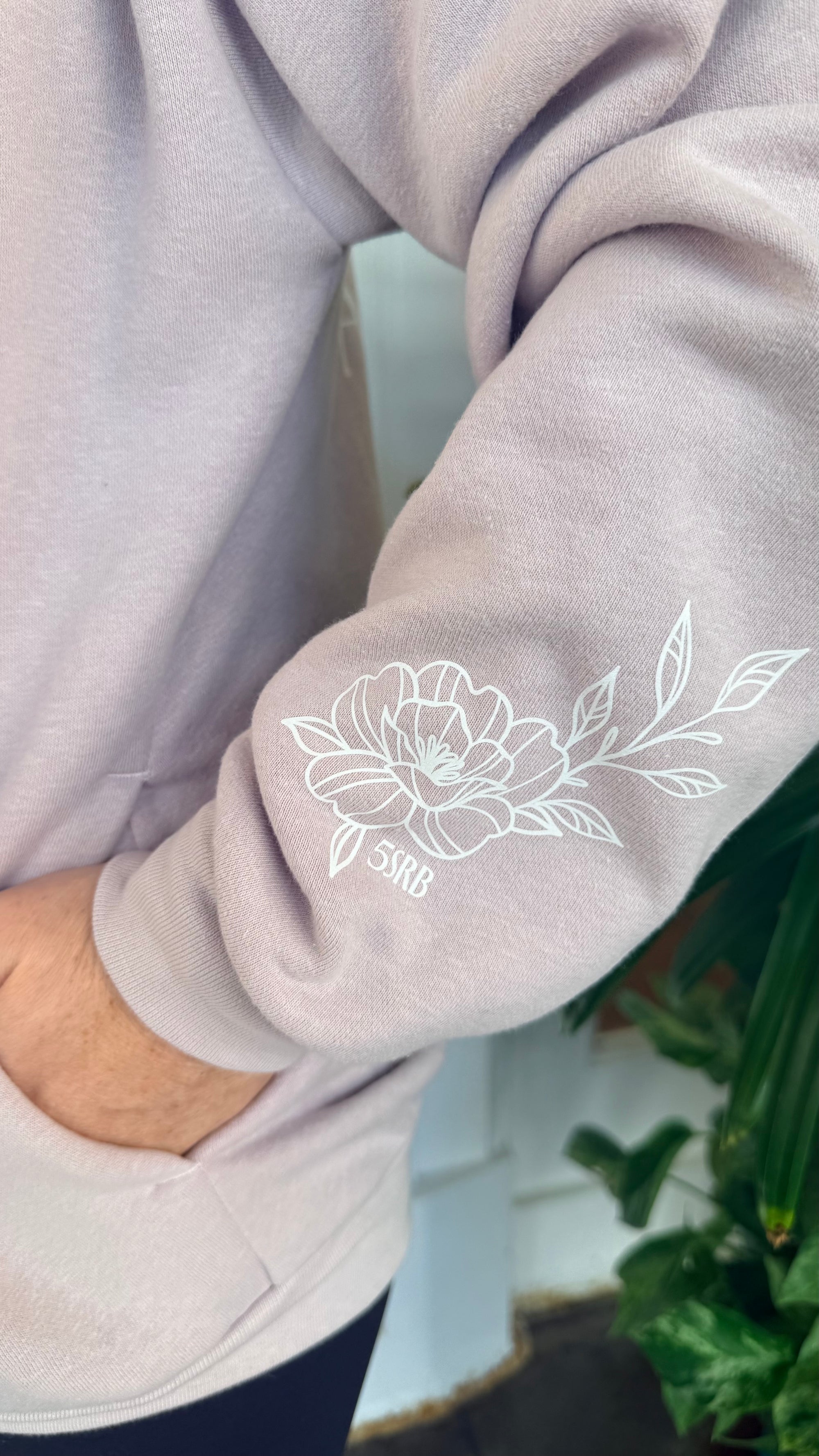 Close-up of a light pink  sweatshirt with a floral design on the sleeve.
