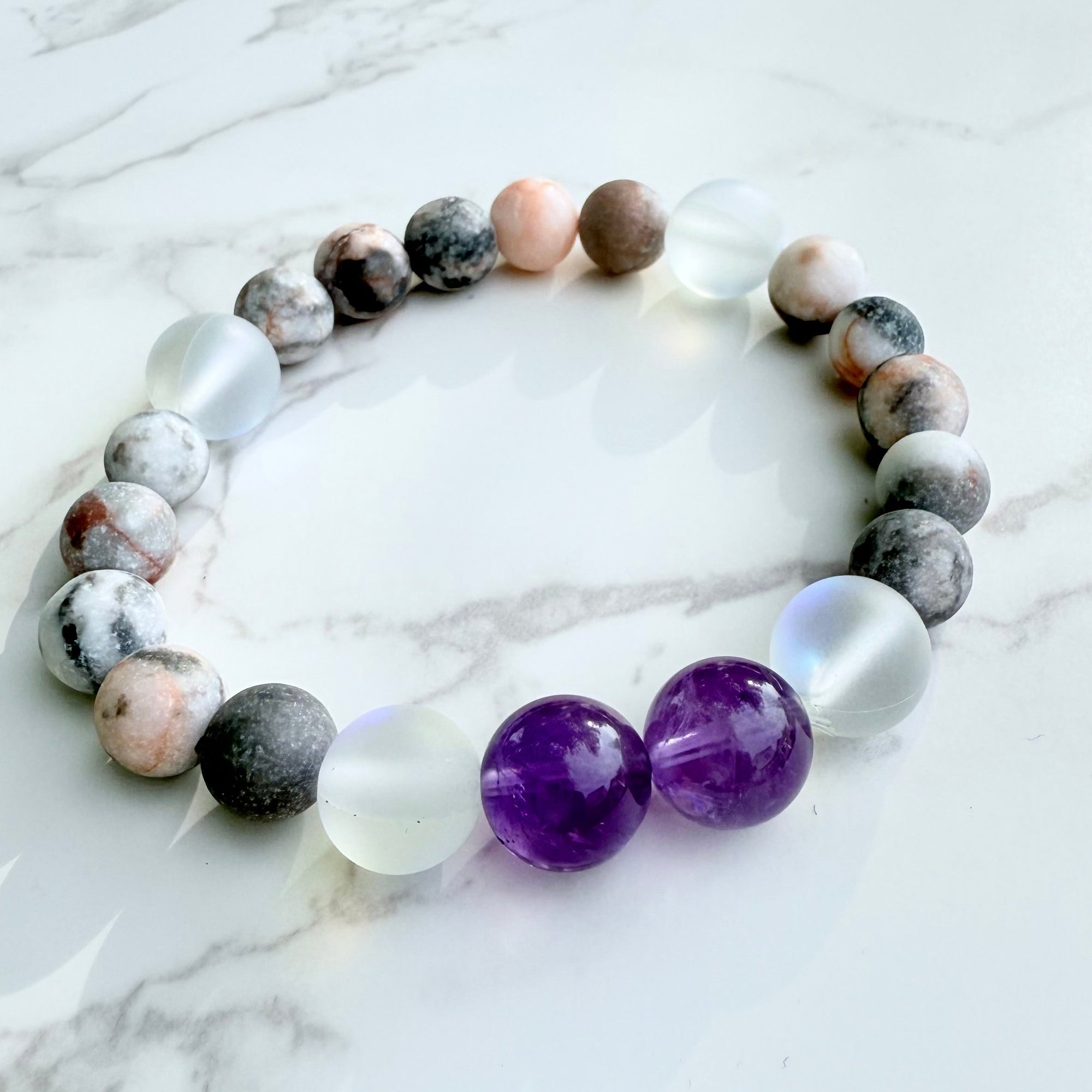 Beaded bracelet with purple and clear beads on a marble surface