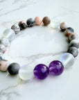 Beaded bracelet with purple and clear beads on a marble surface