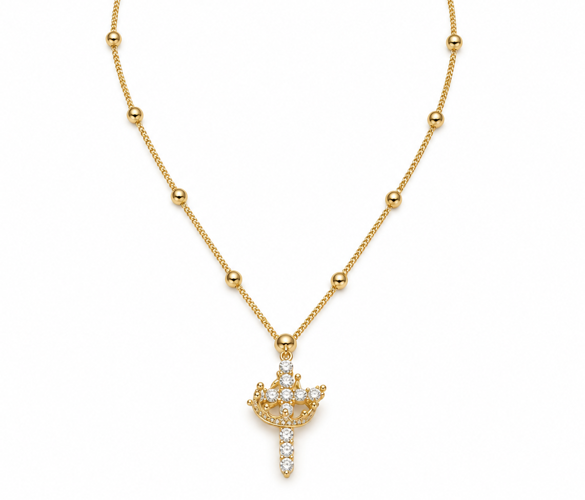 A gold beaded chain necklace with a crown-shaped pendant paved with clear crystals, displayed on a clean white background.
