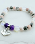 Beaded bracelet with a 'Daughter' charm on a marble surface
