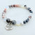 Bracelet with gray and white beads and a 'Daughter In Law' charm on a light background