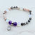 Beaded bracelet with purple charm on a marble surface