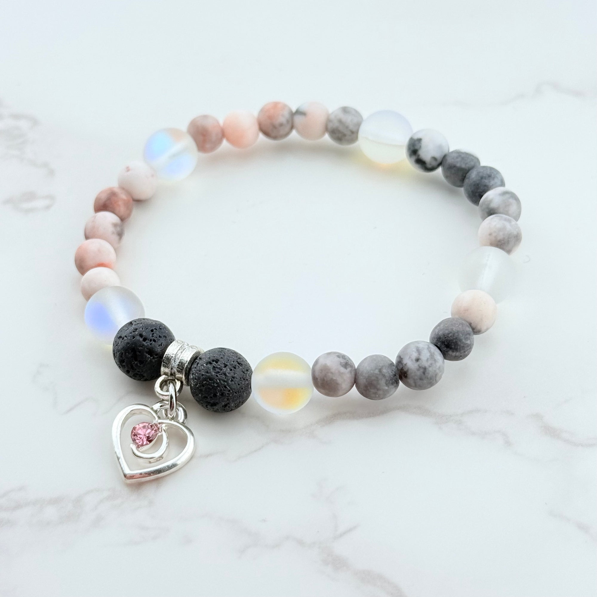 Beaded bracelet with a heart charm on a marble surface