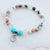 Beaded bracelet with turquoise beads and a heart charm on a marble surface