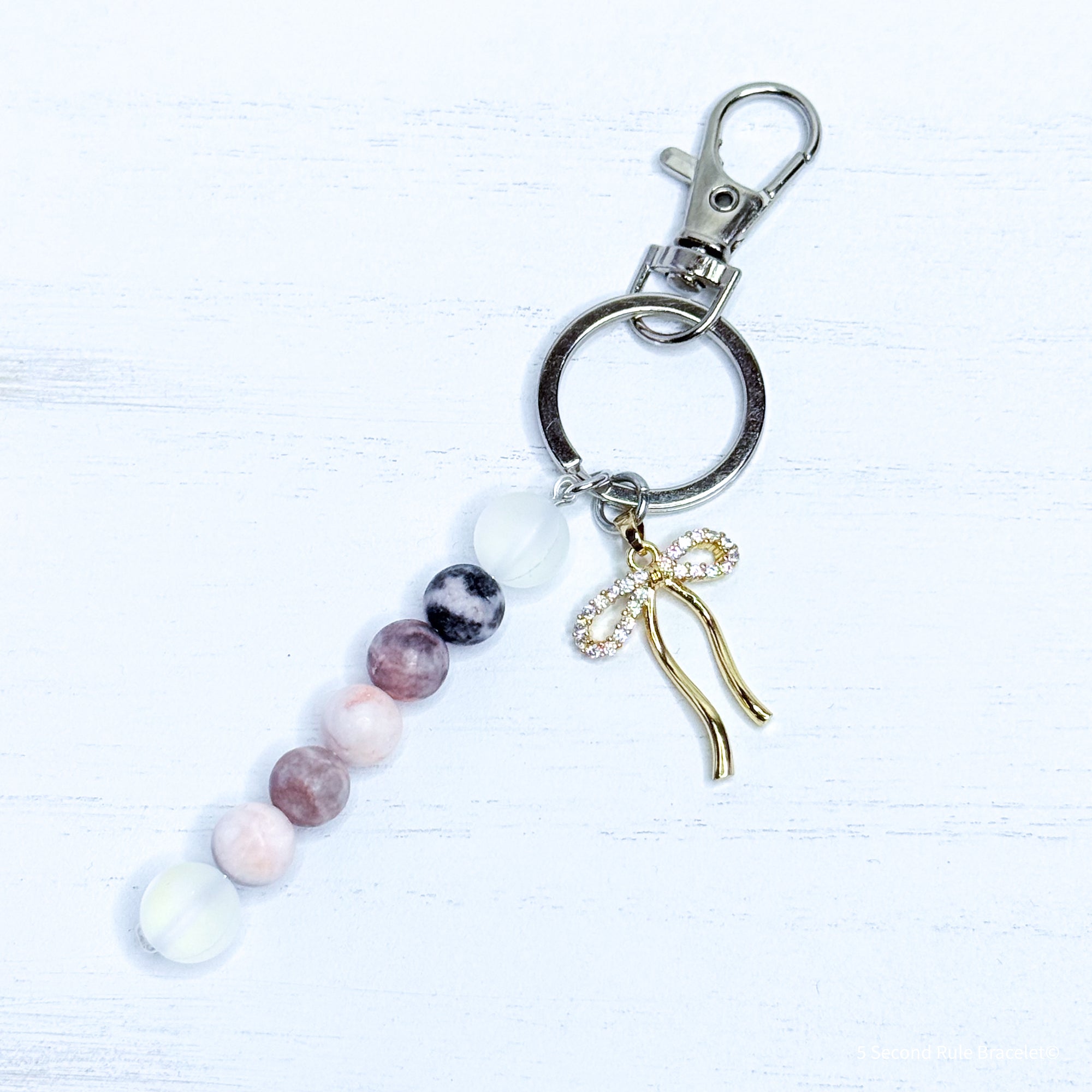 Keychain with beads and a gold bow charm on a white background