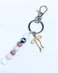 Keychain with beads and a gold bow charm on a white background