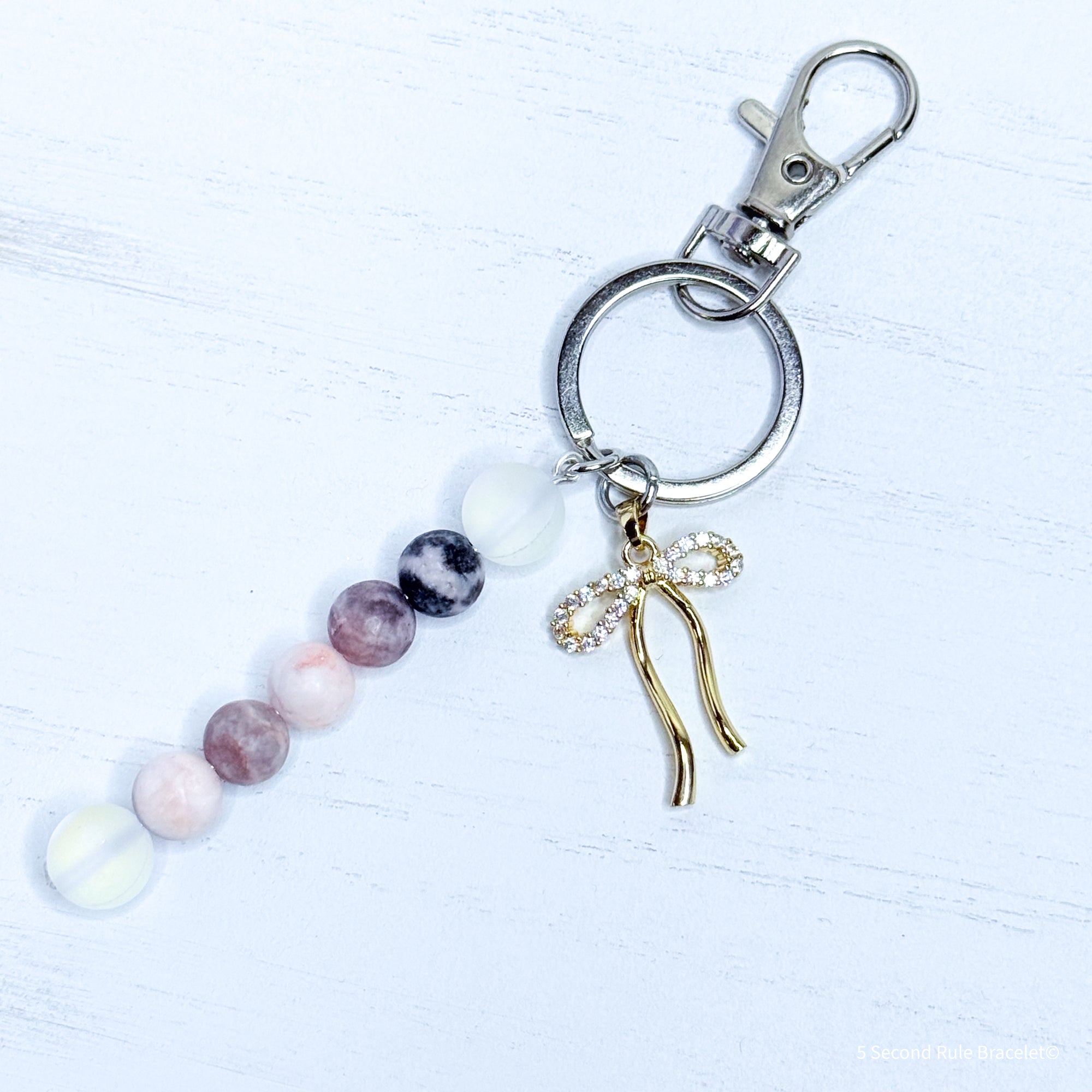 Keychain with beads and a gold bow charm on a white background