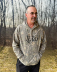 Man wearing a camouflage hoodie with text in a forest setting