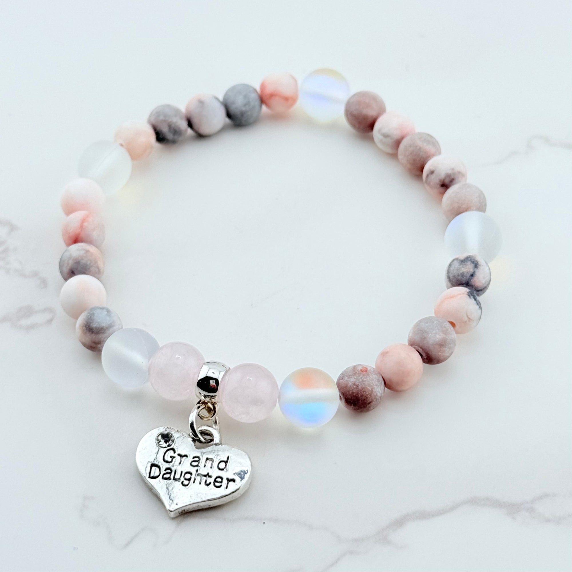 Beaded bracelet with a 'Granddaughter' heart charm on a marble surface