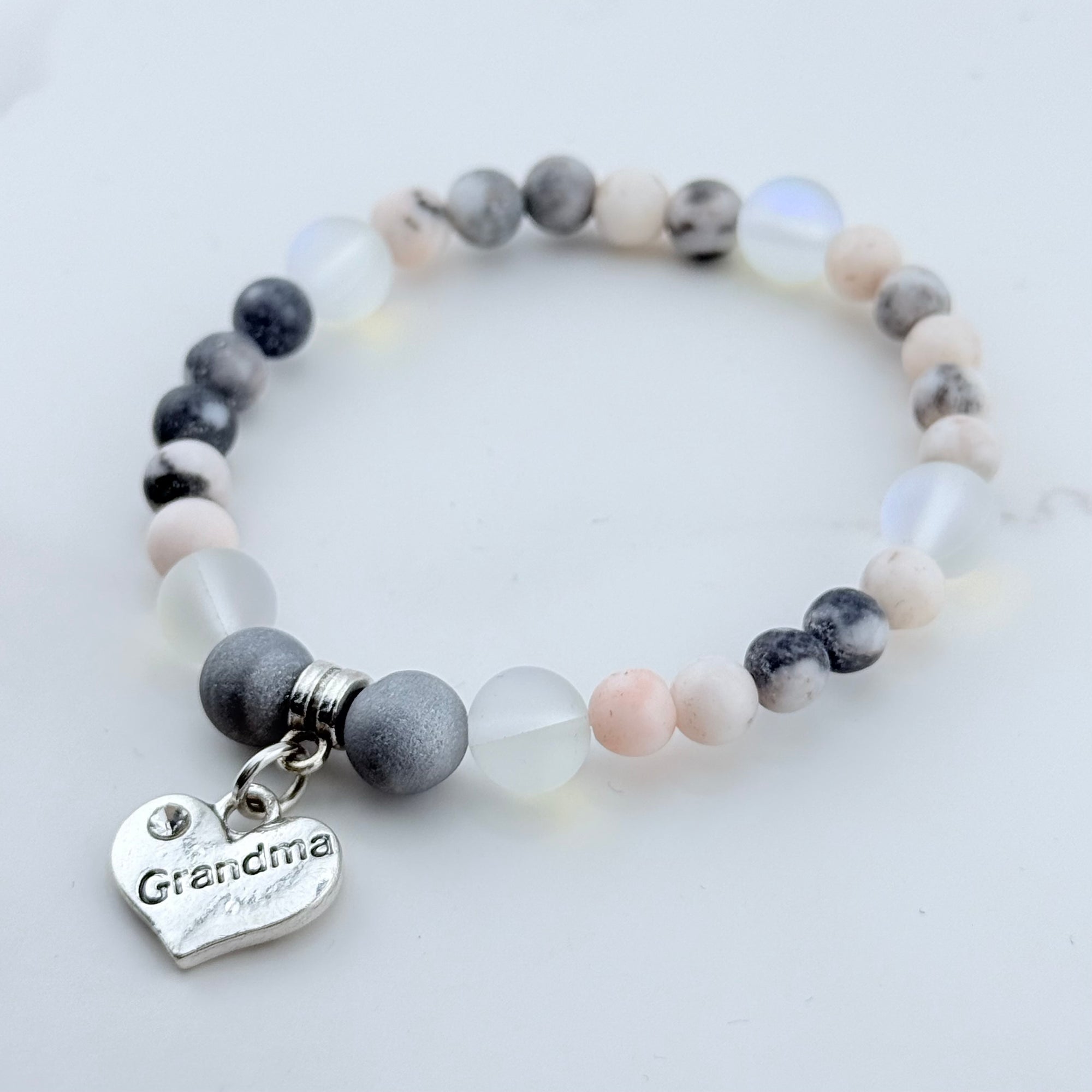 Bracelet with gray and white beads and a 'Grandma' charm on a light background