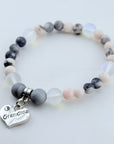 Bracelet with gray and white beads and a 'Grandma' charm on a light background