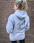 Person wearing a gray hoodie with 'Just Pray' text on the back against a brick wall.