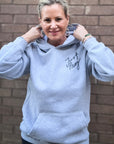 Person wearing a gray hoodie with 'Just Pray' text, standing against a brick wall.