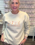 Woman wearing a light-colored sweatshirt with 'He is Risen' text and leopard print pants in a store setting.
