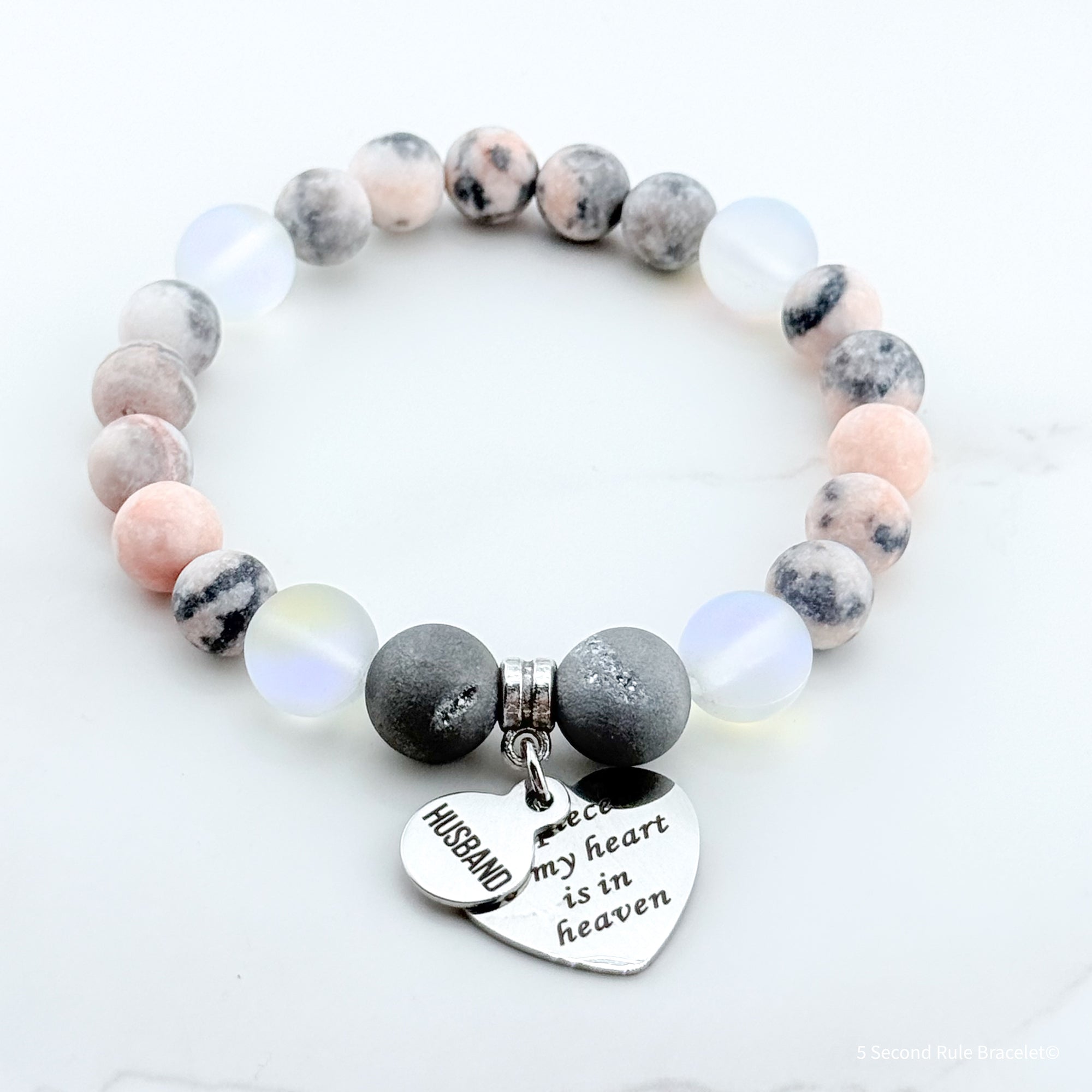 Beaded bracelet with heart-shaped charm and engraved text on a white background