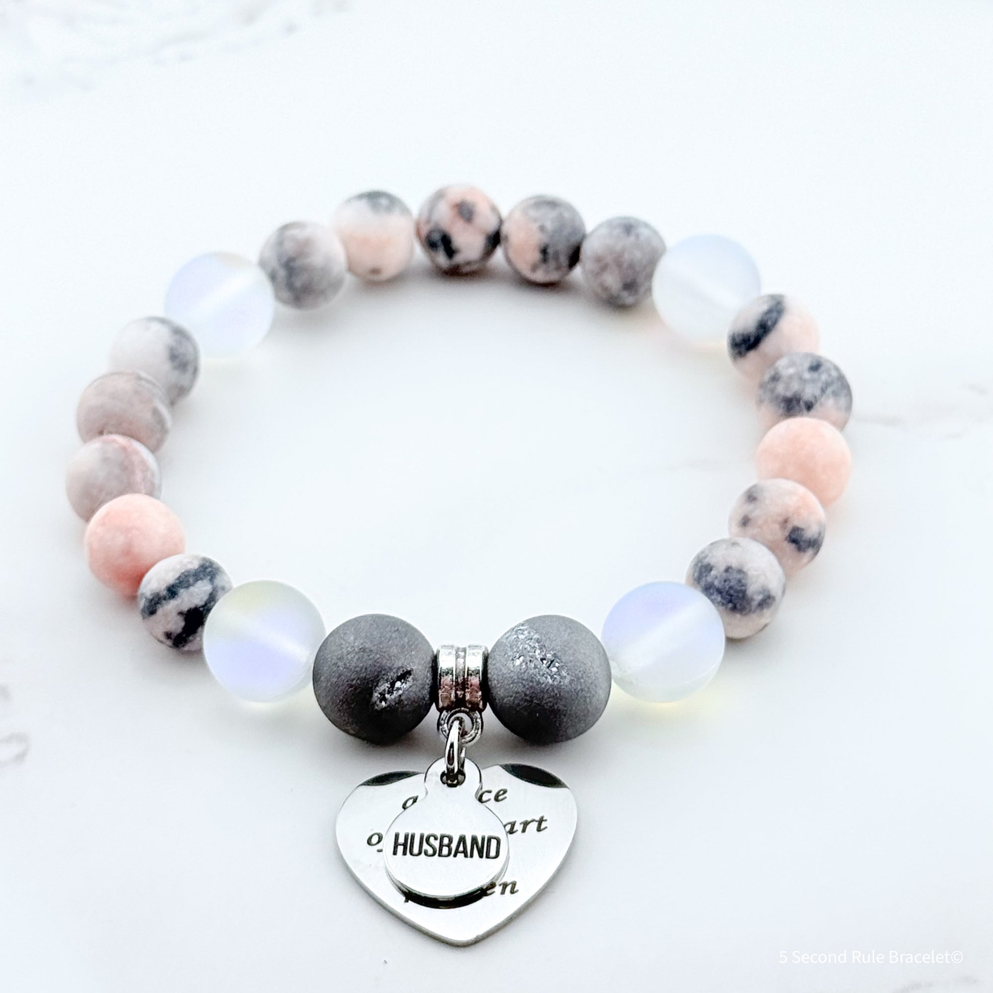 Marble beaded bracelet with a heart-shaped charm on a white background