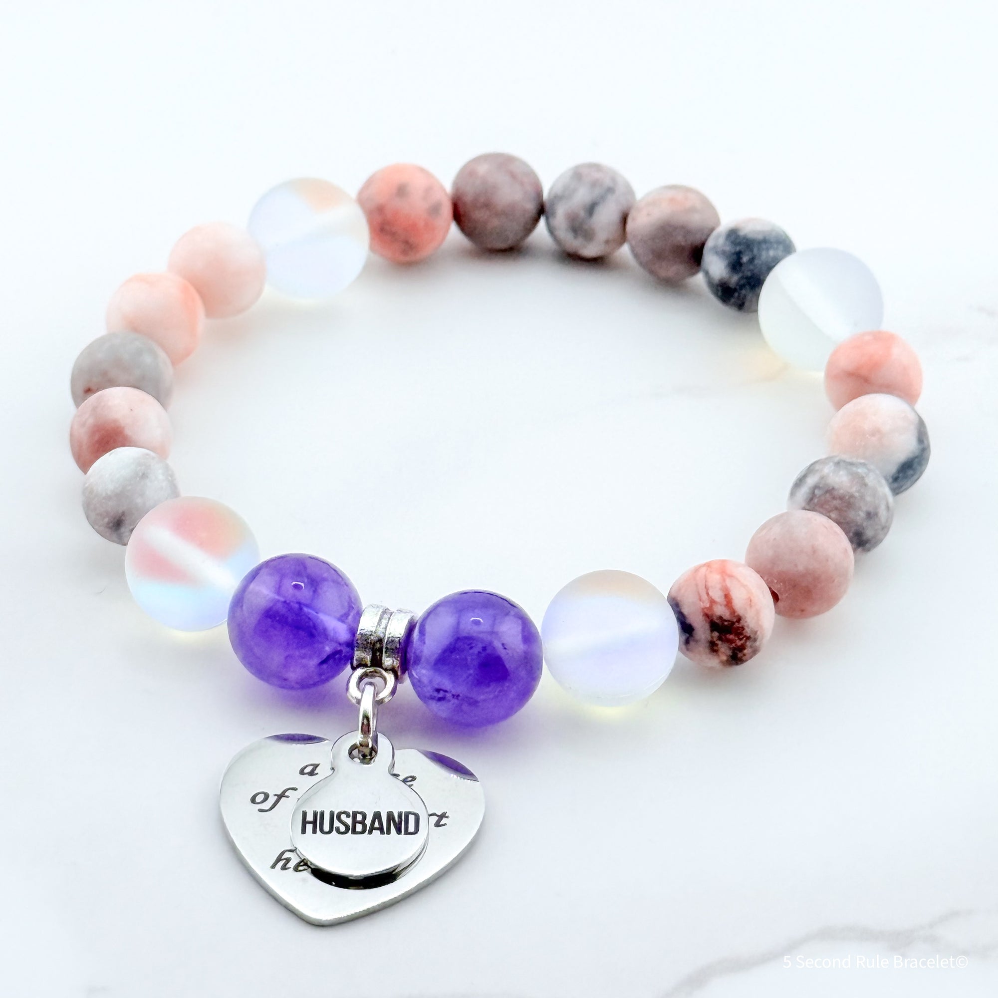 Multicolored beaded bracelet with a heart-shaped charm on a white background