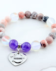 Multicolored beaded bracelet with a heart-shaped charm on a white background