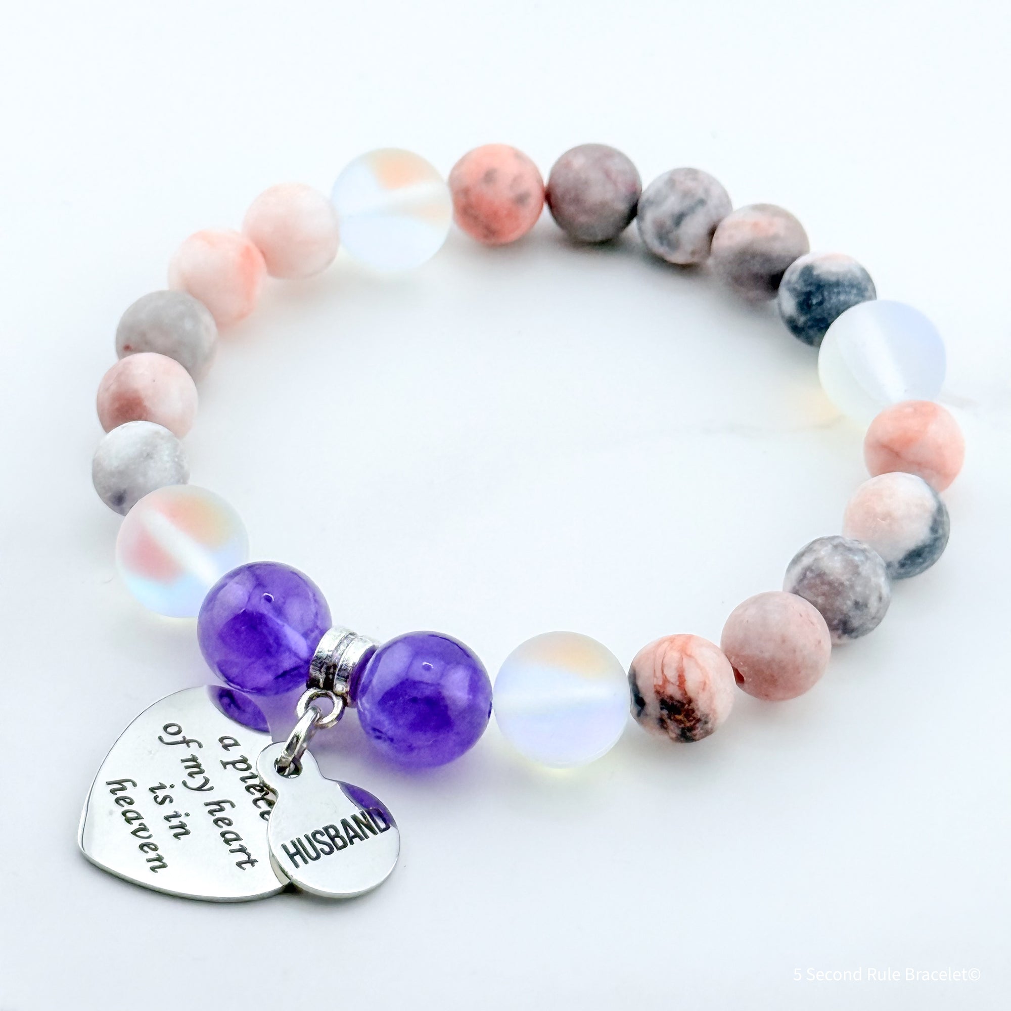 Multicolored beaded bracelet with heart and round charms on a white background