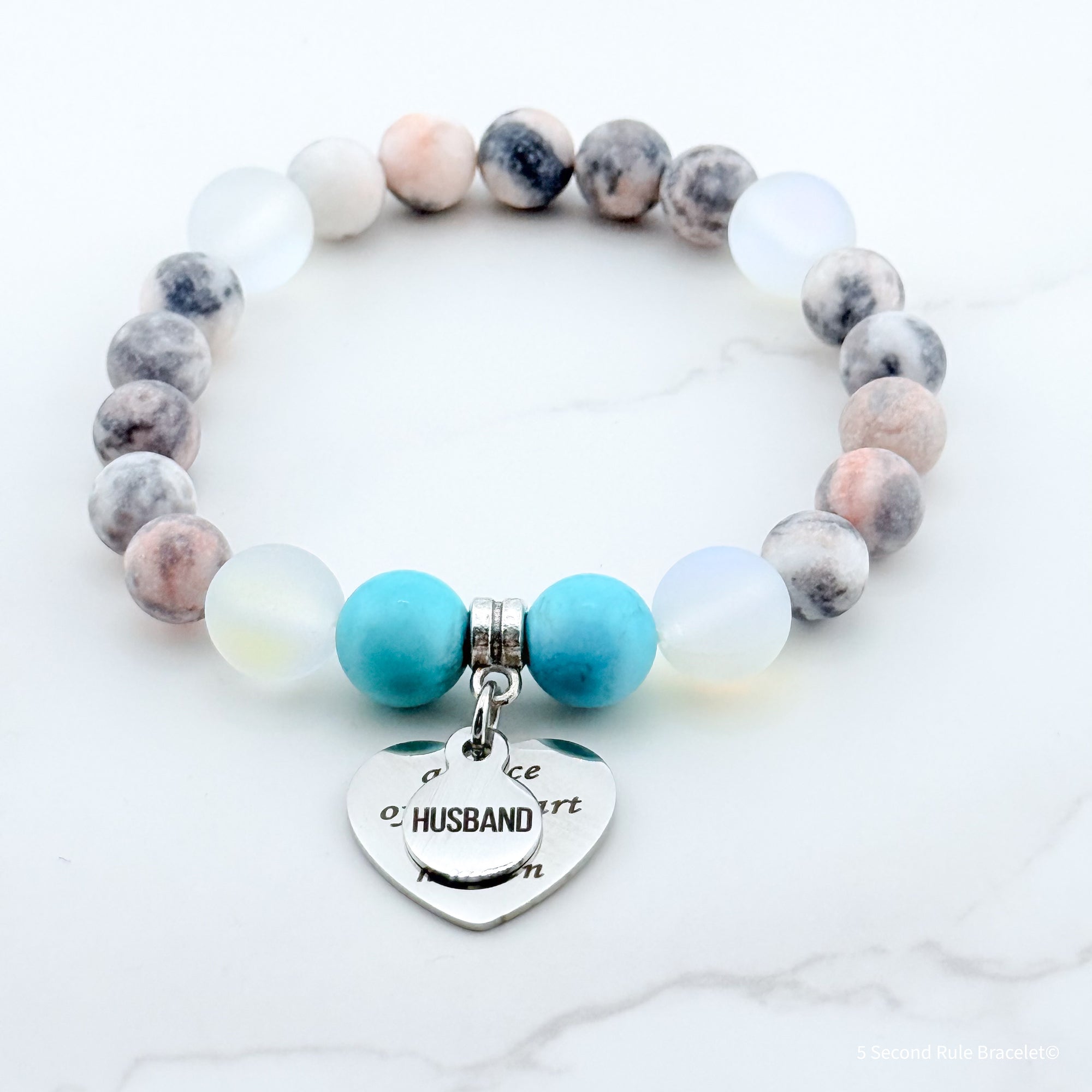 Bracelet with multicolored beads and a heart-shaped charm on a white background