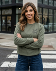 Woman wearing a green sweatshirt with text, standing on a city street.