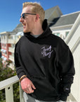 Man wearing a black hoodie with 'Just Stay' text on a balcony