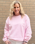 Woman wearing a pink sweatshirt standing in front of a brick wall