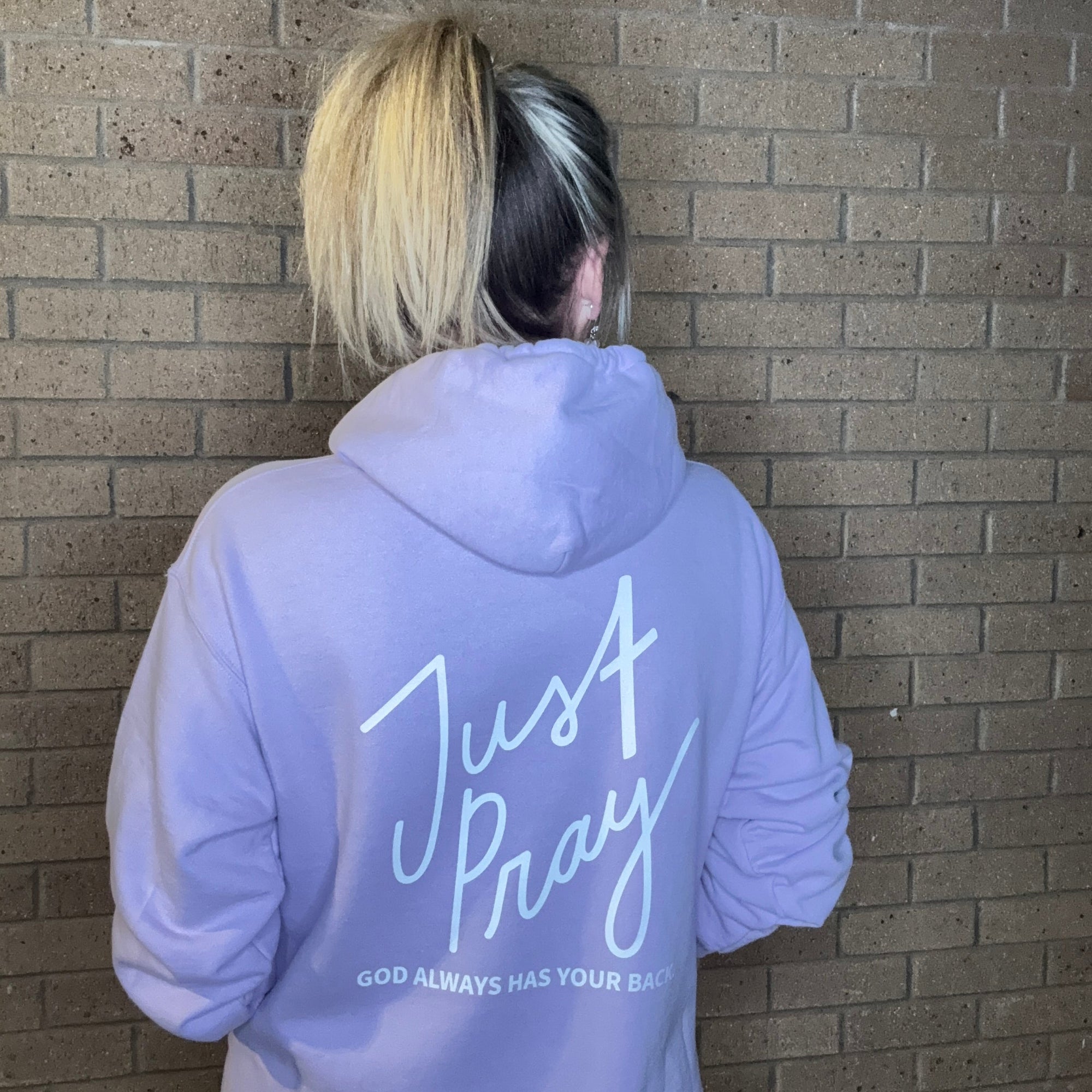Person wearing a lavender hoodie with 'Just Pray' text on a tiled floor.