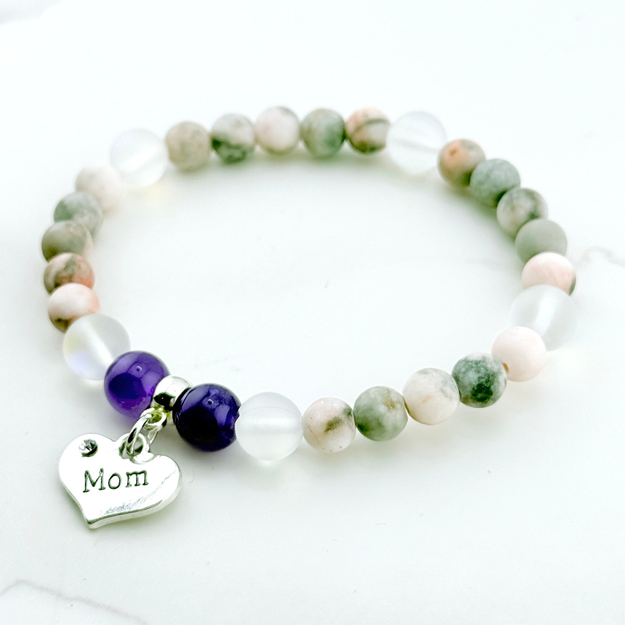 Beaded bracelet with 'Mom' charm on a light background