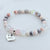 Beaded bracelet with a 'Mom' charm on a light background
