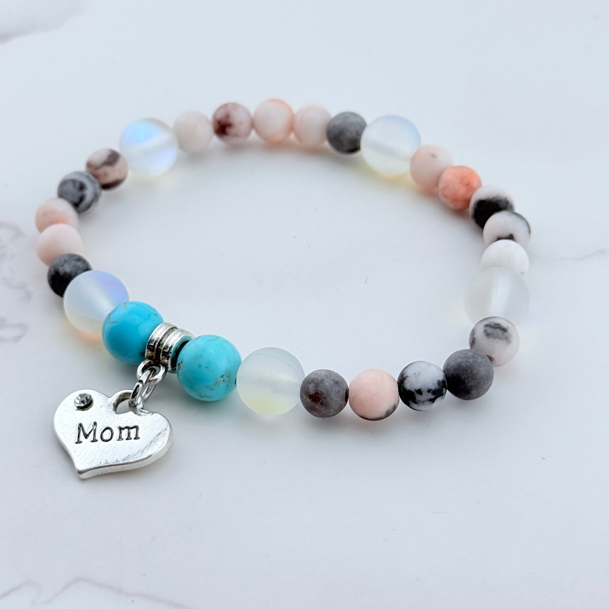 Multicolored beaded bracelet with a 'Mom' charm on a light background