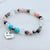 Multicolored beaded bracelet with a 'Mom' charm on a light background