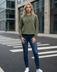 Woman wearing a green sweatshirt with 'Praise the Lord' text on a city street.