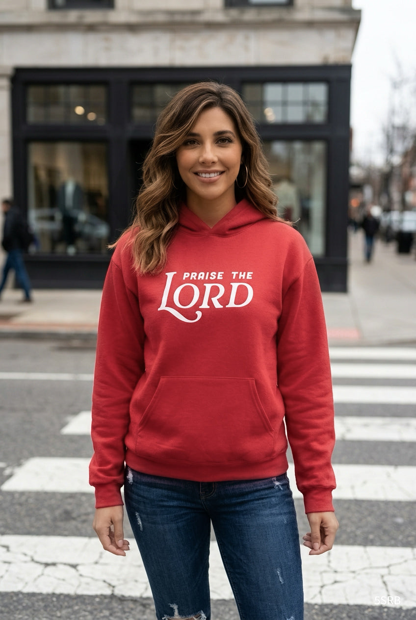 Woman wearing a red hoodie with 'Praise the Lord' text on a city street.