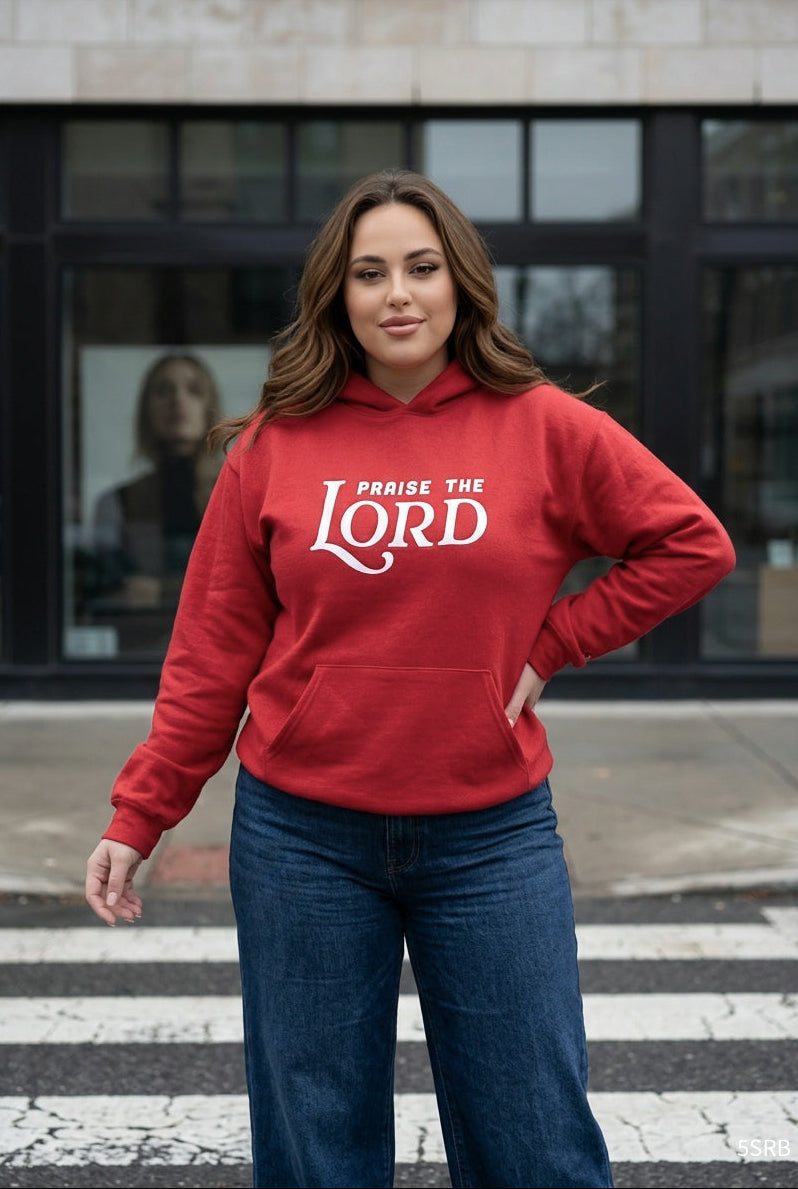 Woman wearing a red hoodie with 'Praise the Lord' text on a city street.