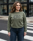 Woman wearing a green sweatshirt with 'Praise the Lord' text on a city street.