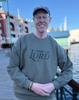 Man wearing a sweatshirt with 'Praise the Lord' text by a waterfront.