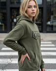 Woman wearing a green hoodie with 'Praise the Lord' text on a street.