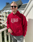 Man wearing a red hoodie with 'PRAISE THE LORD' text on a balcony.