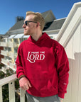 Man wearing a red hoodie with 'Praise the Lord' text on a balcony.