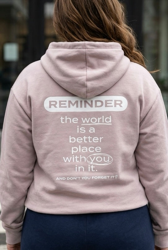 Person wearing a light pink hoodie with a motivational message on the back.